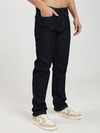 man wearing dark blue jeans and white sneakers on a white background