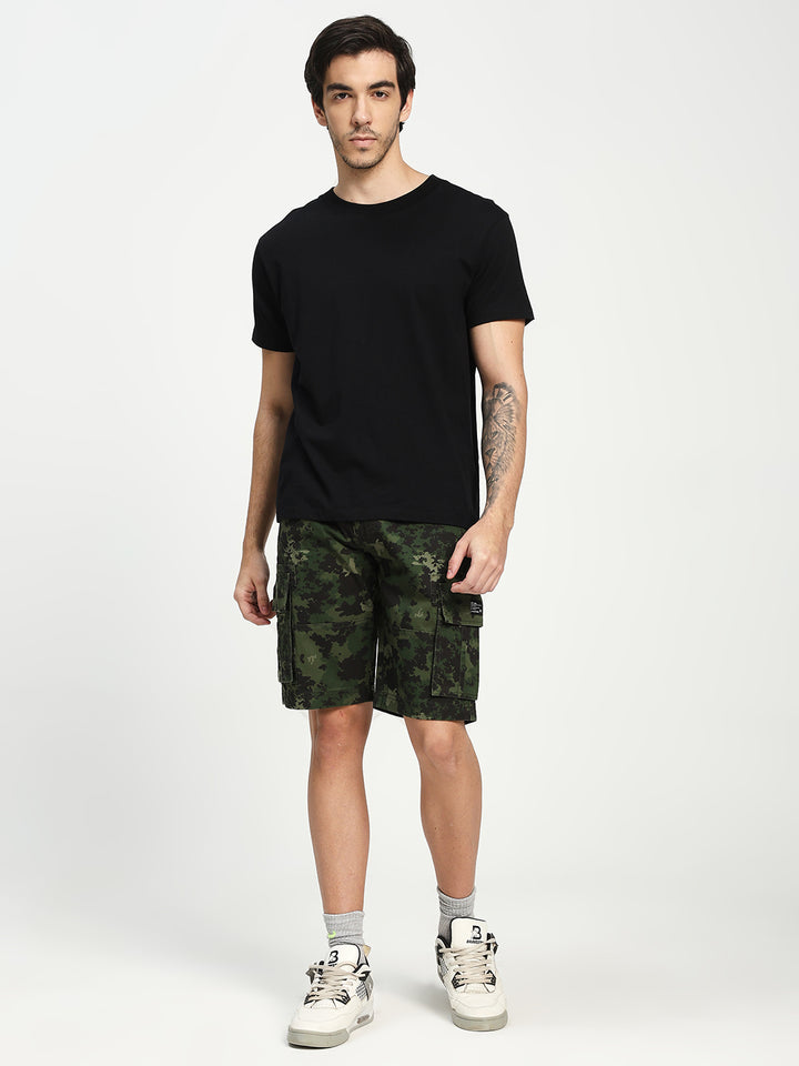 Man wearing a black t-shirt and camouflage shorts on a white background