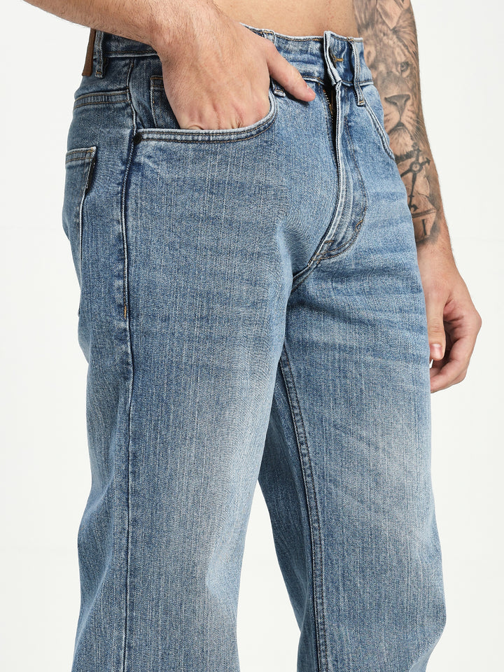 man wearing light blue bootcut jeans with a white background