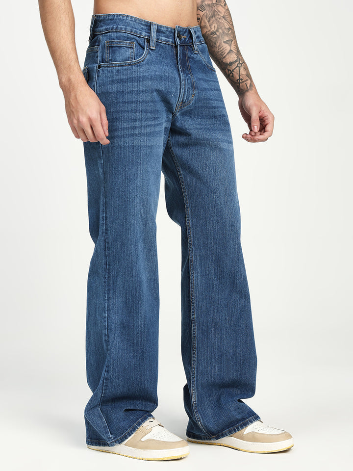 man wearing blue bell bottom jeans on a white background