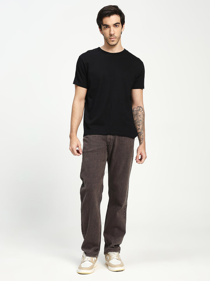 Man wearing a black t-shirt and dark brown ecru jeans on a white background