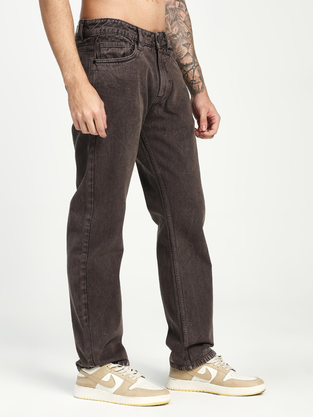 man wearing dark brown ecru jeans and beige sneakers on a white background