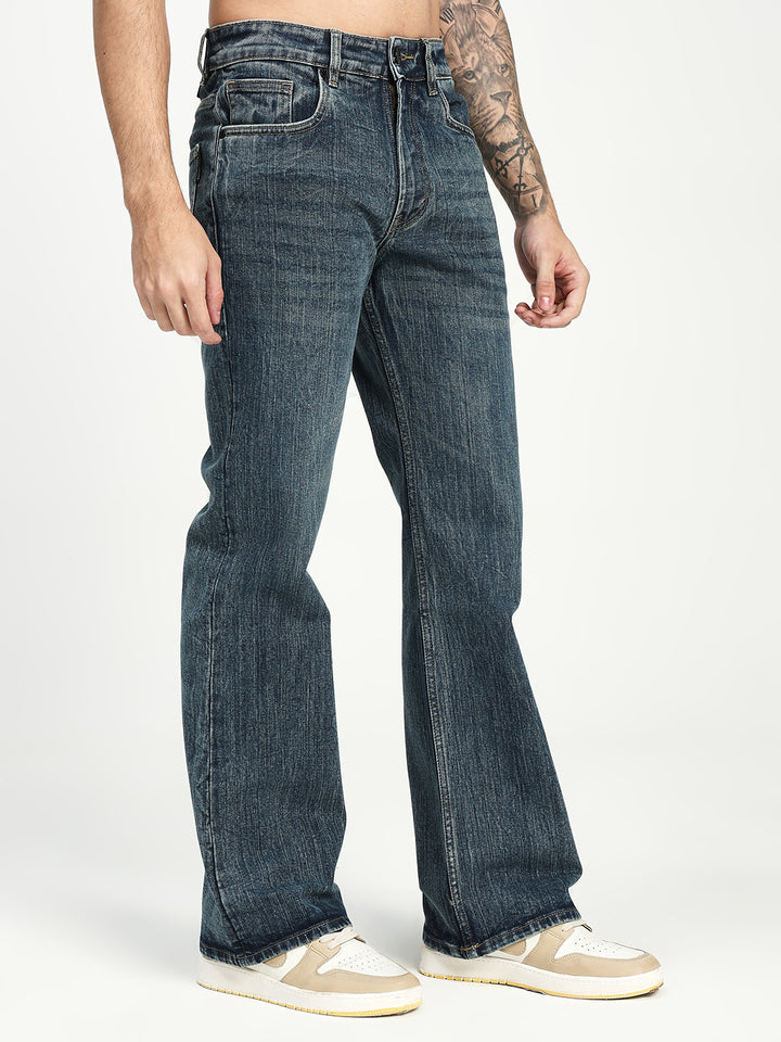 man wearing dark blue bootcut jeans on a white background
