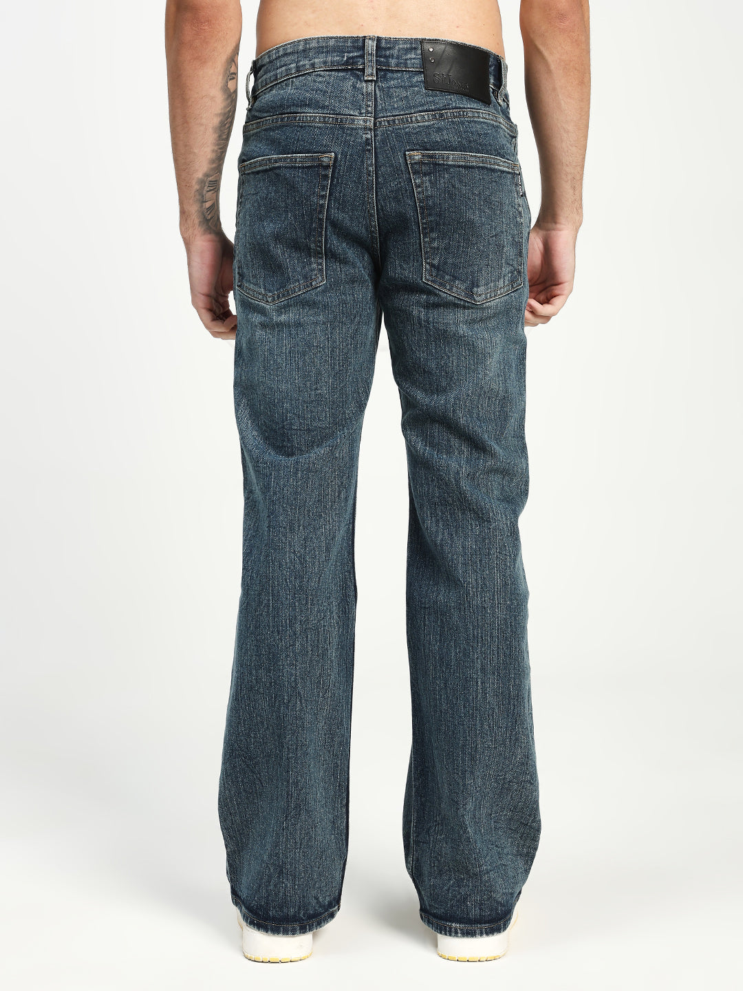 man wearing dark blue bootcut jeans on a white background