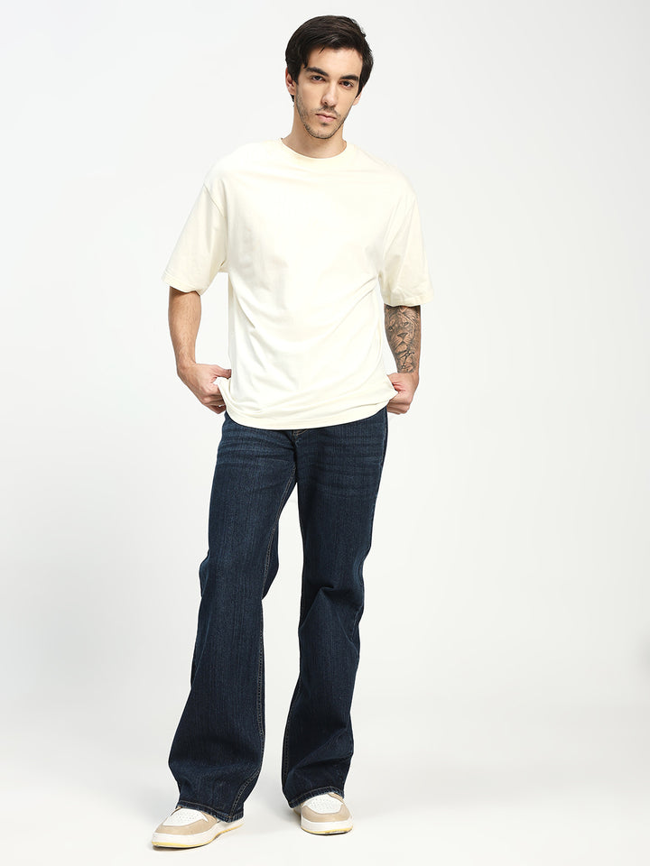 Man wearing a white t-shirt and bell bottom blue jeans on a white background