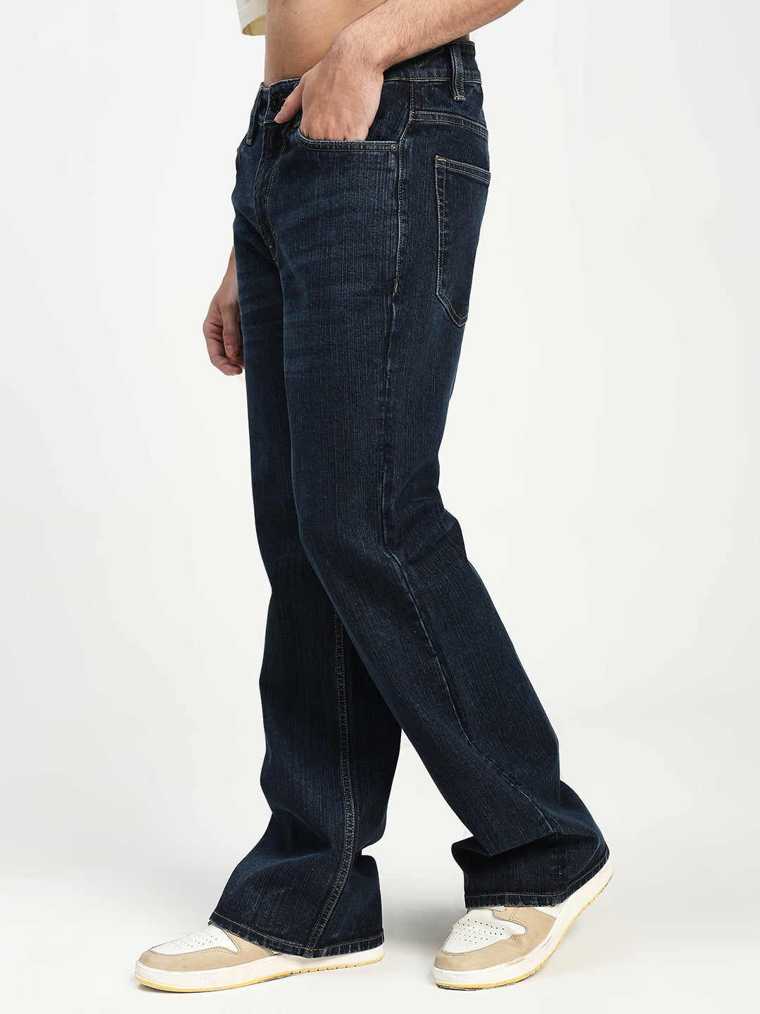 man wearing dark blue bell bottom jeans on a white background