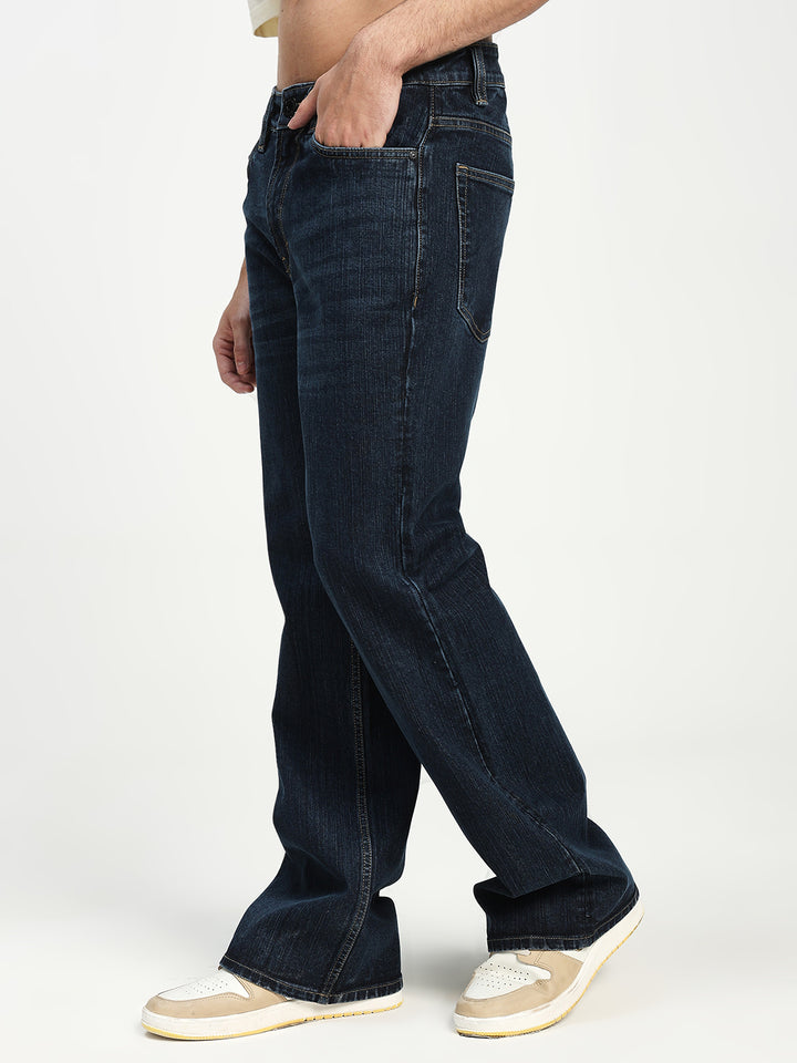 man wearing dark blue bell bottom jeans on a white background