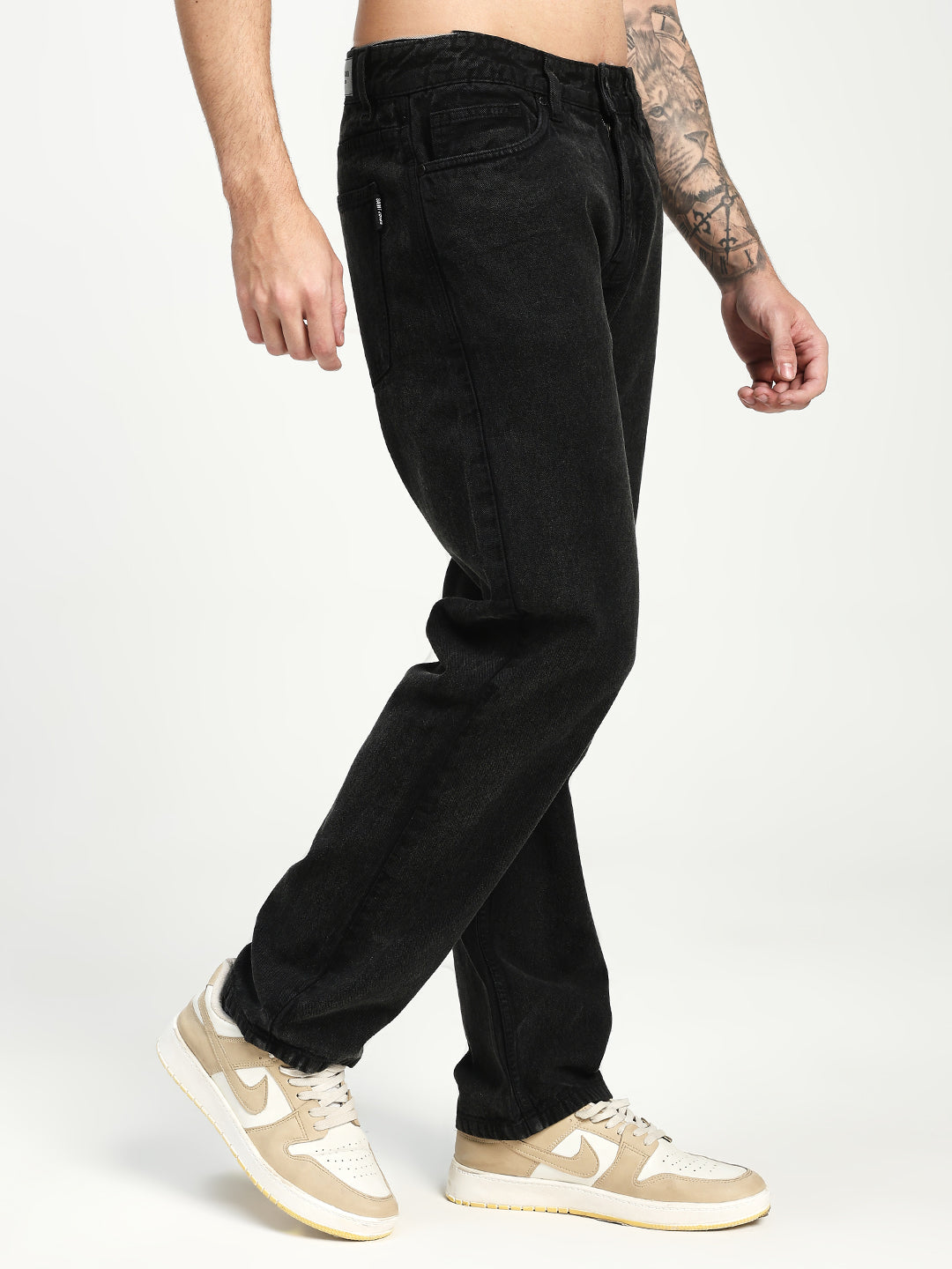 man wearing black ecru jenas and beige sneakers on a white background