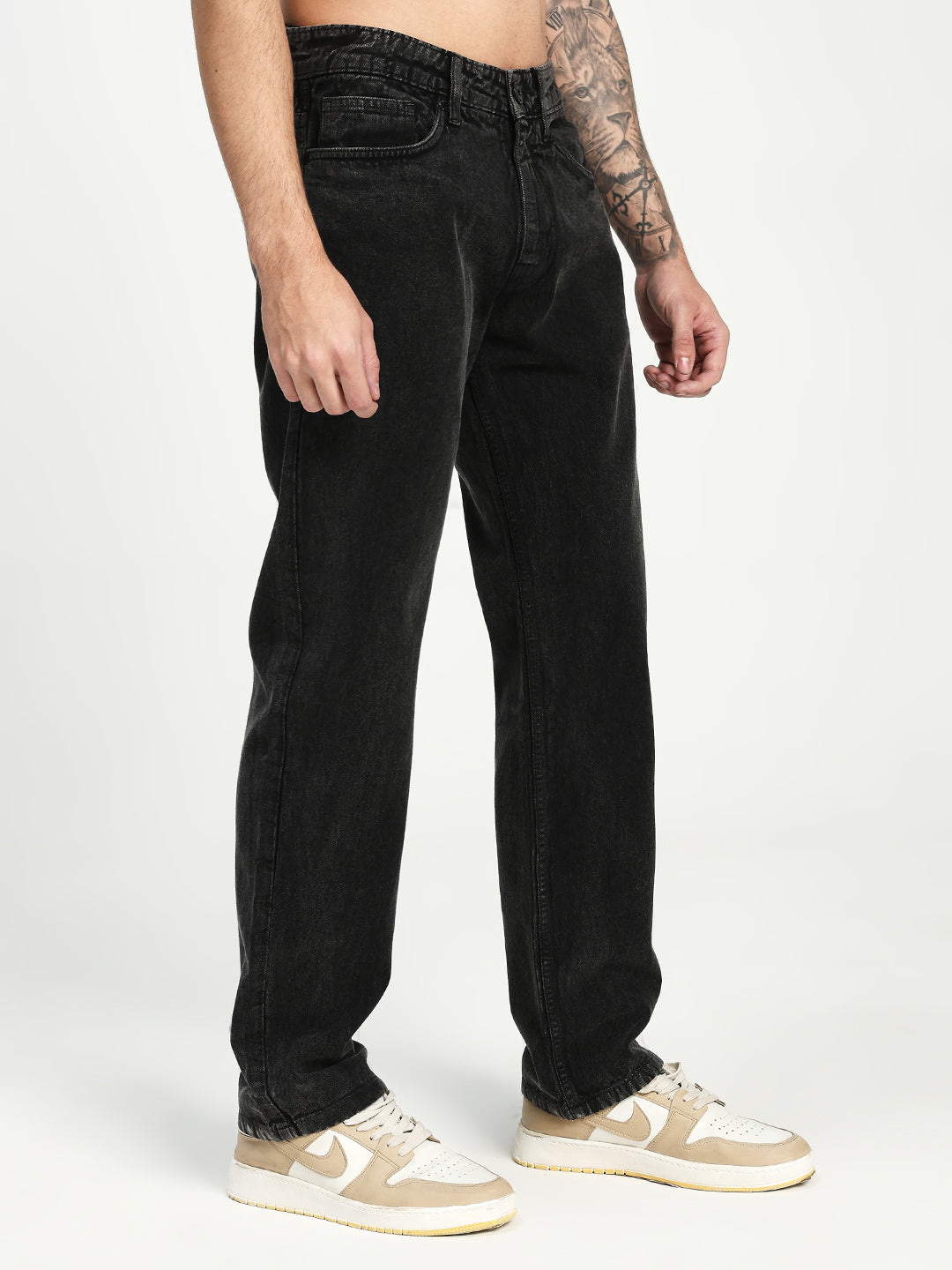 man wearing charcoal acru jeans and beige sneakers on a white background