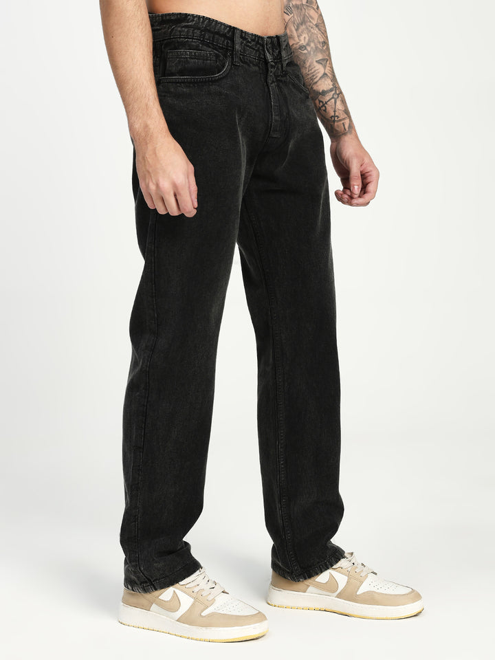 man wearing charcoal acru jeans and beige sneakers on a white background