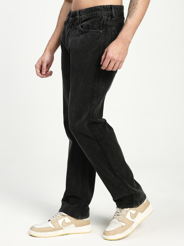 man wearing charcoal acru jeans and beige sneakers on a white background