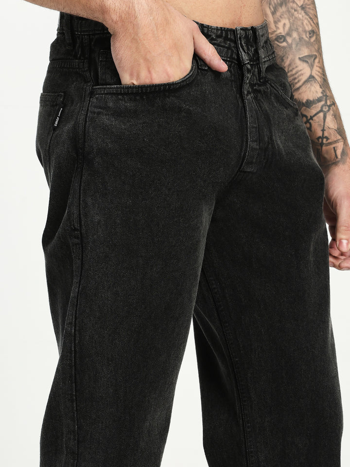 man wearing charcoal acru jeans with a tattooed arm on a white background
