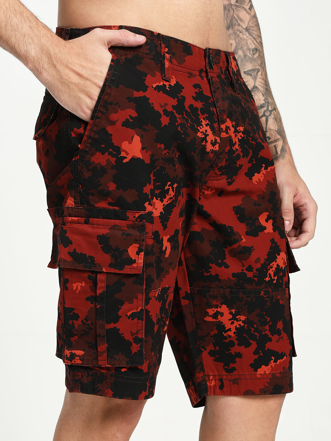 Red and black camouflage cargo shorts worn by a man on a white background