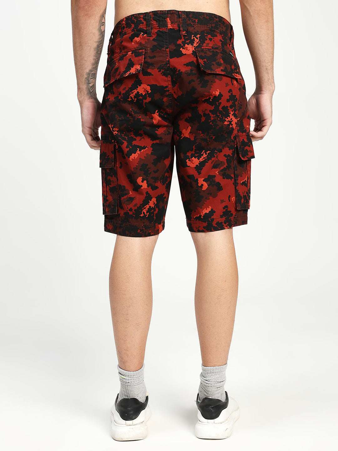 Red and black camouflage cargo shorts worn by a man on a white background