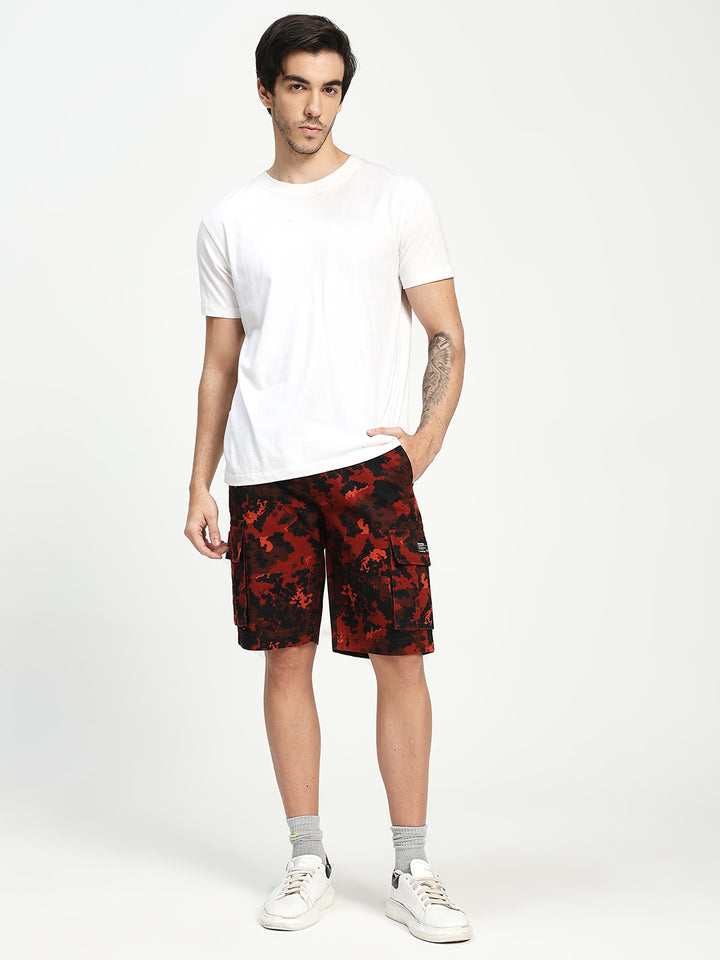 Man wearing a white t-shirt and red camouflage shorts on a white background