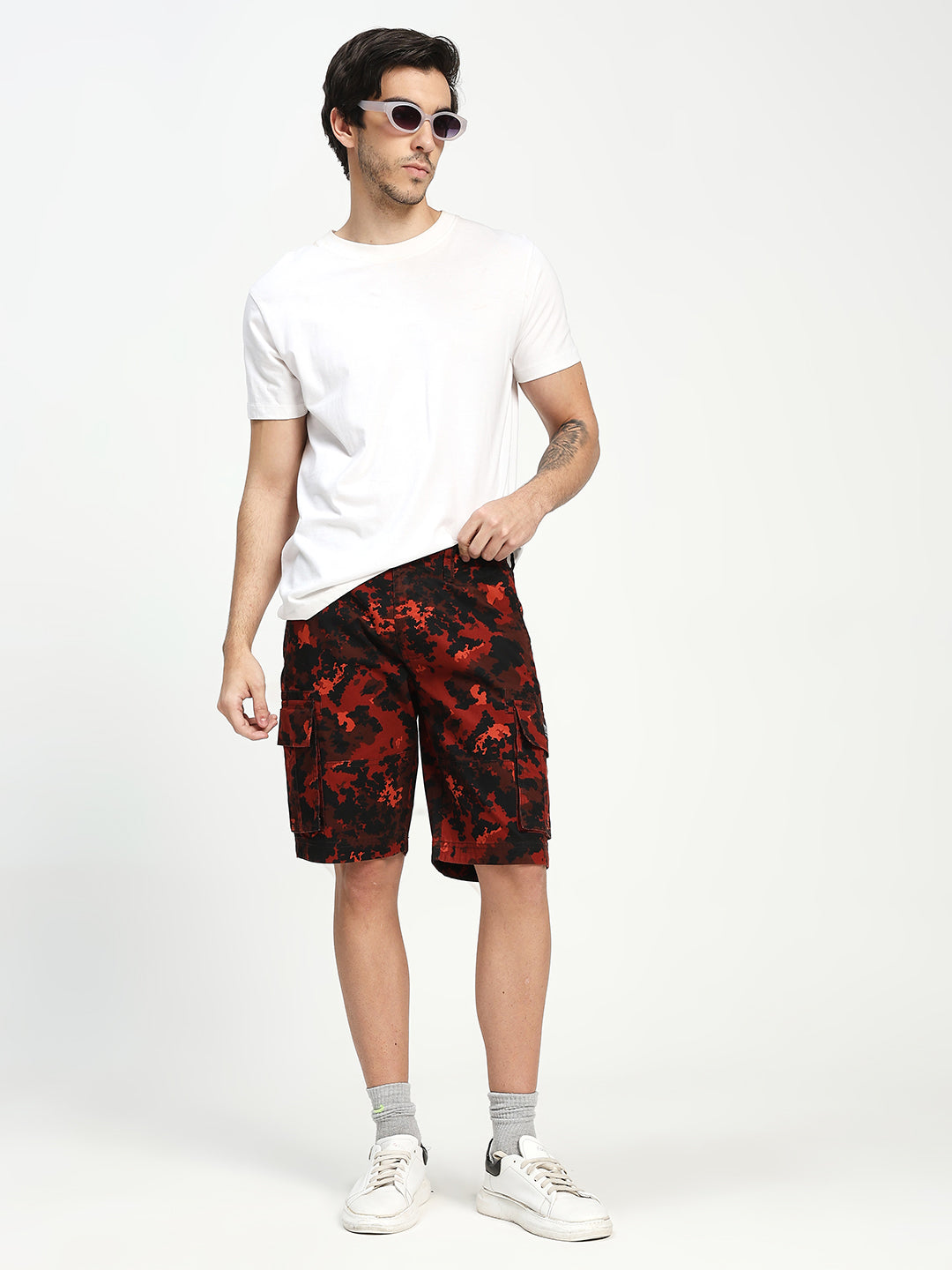 Man wearing a white t-shirt and red camouflage shorts on a white background
