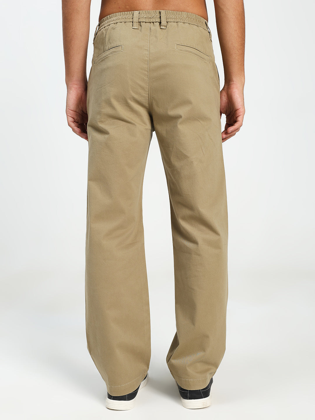 Beige korean pants worn by a man on a white background