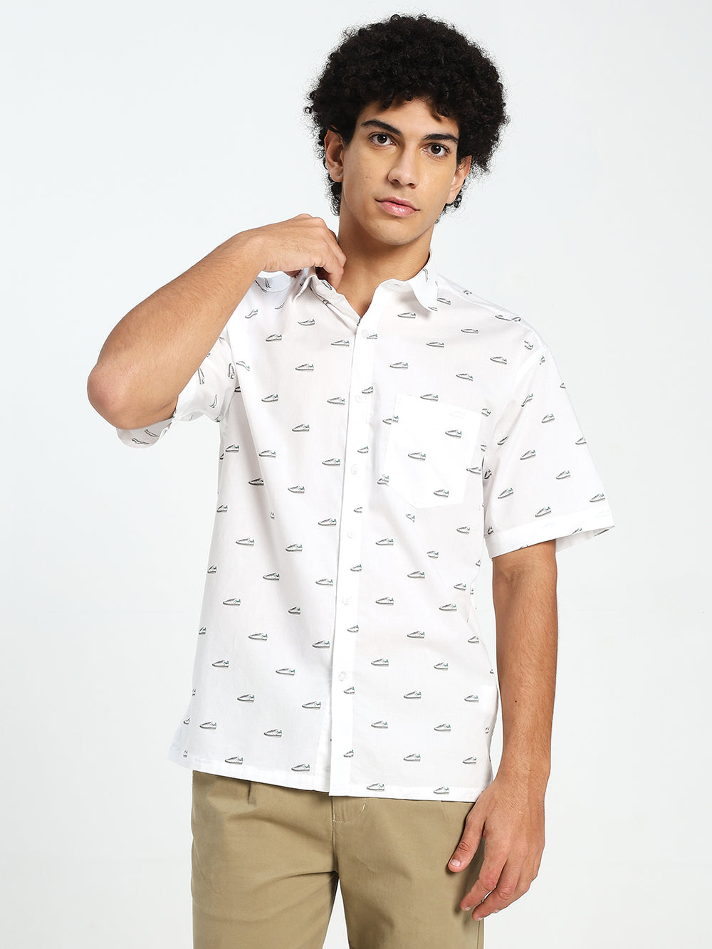 Man wearing a white short-sleeve shirt with a subtle pattern on a plain background