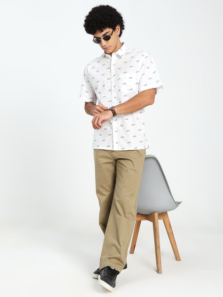Man wearing a white patterned shirt and beige korean pants sitting on a chair against a white background