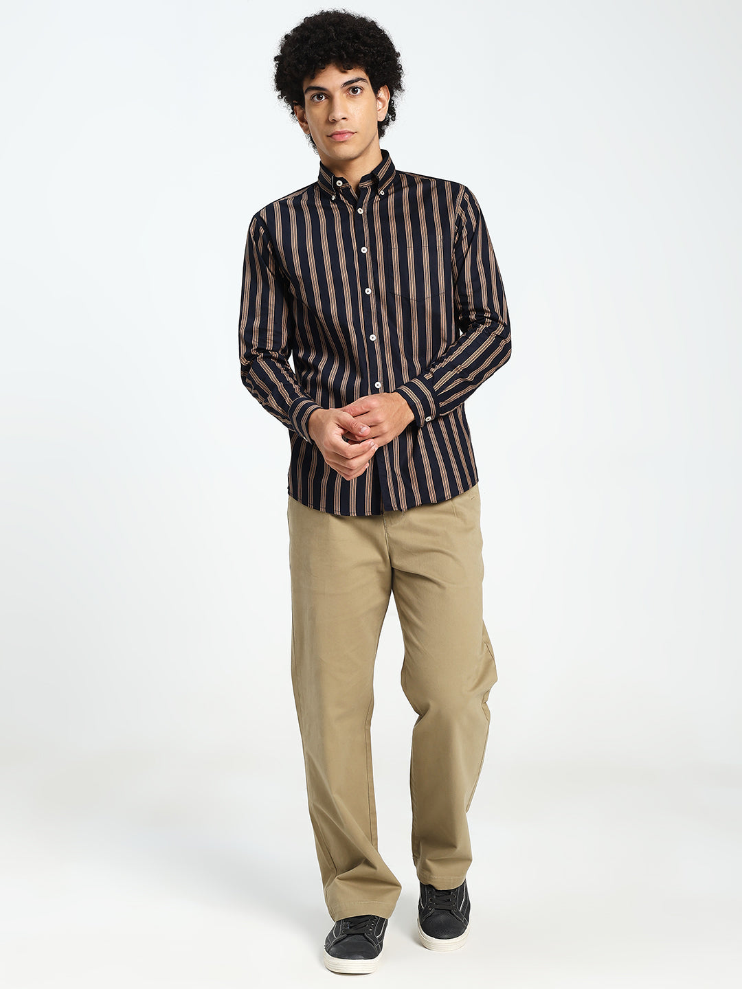 Man wearing a striped shirt and beige pants on a white background