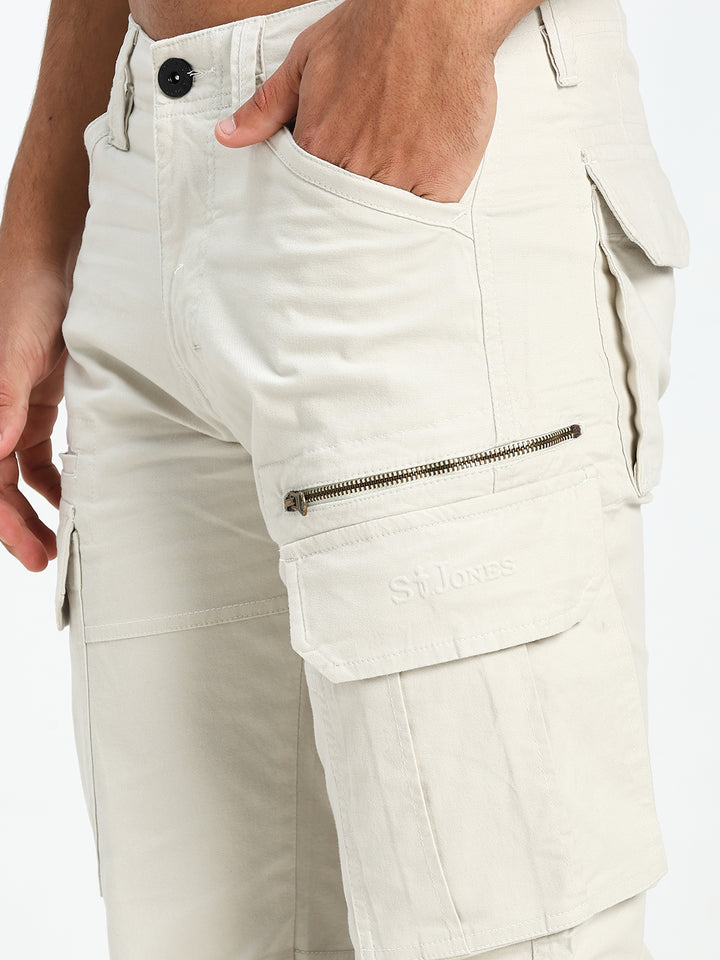 Close-up of cream cargo pants with zippers and buttons on a white background