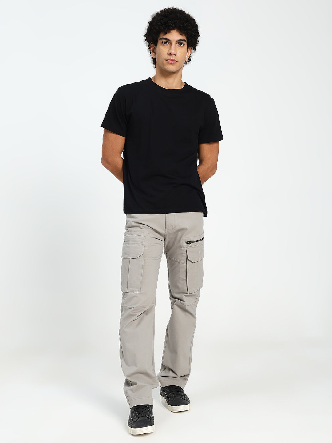 Person wearing a black t-shirt and gray cargo pants on a white background