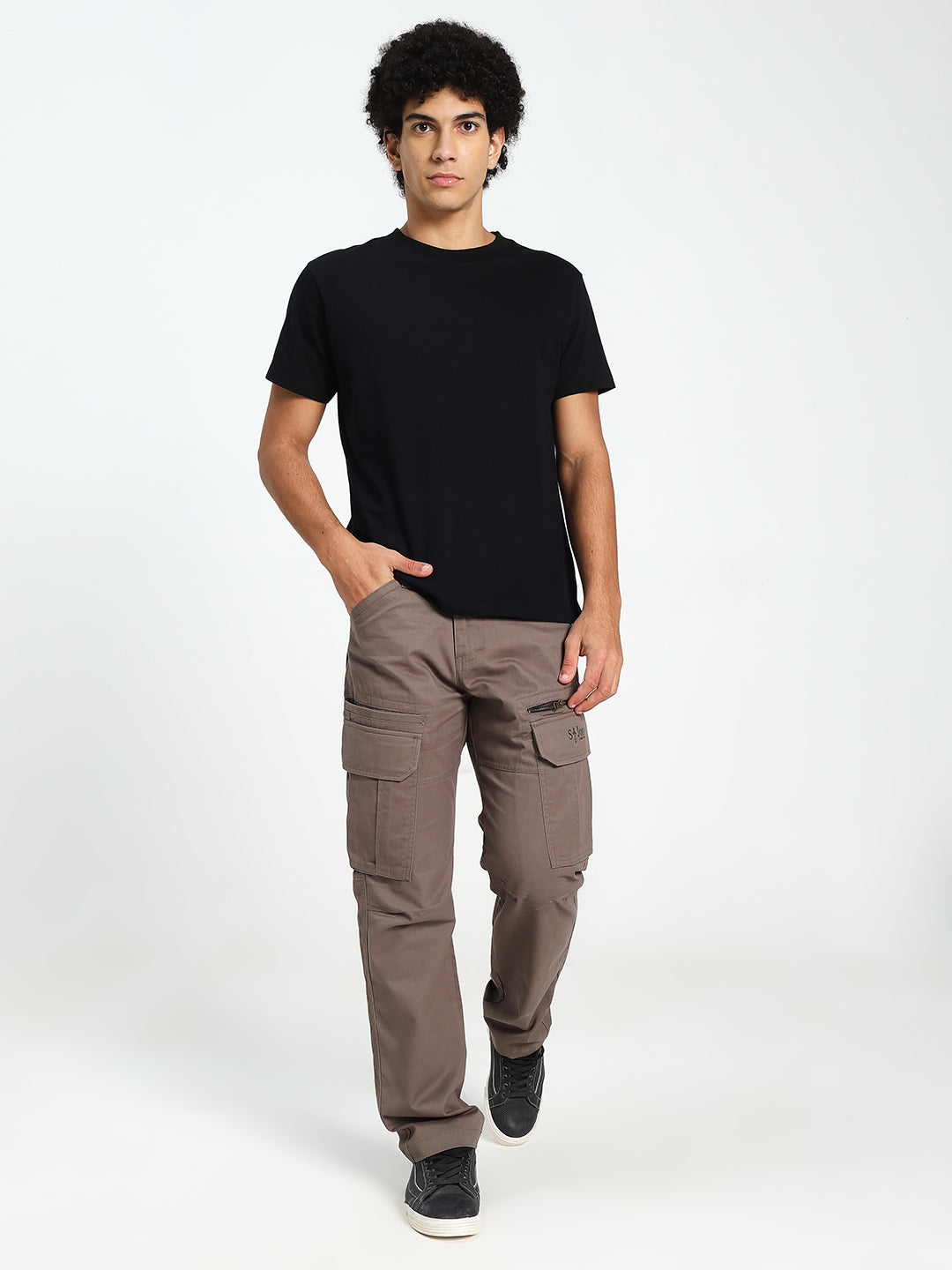 man wearing a black t-shirt and brown cargo pants on a white background