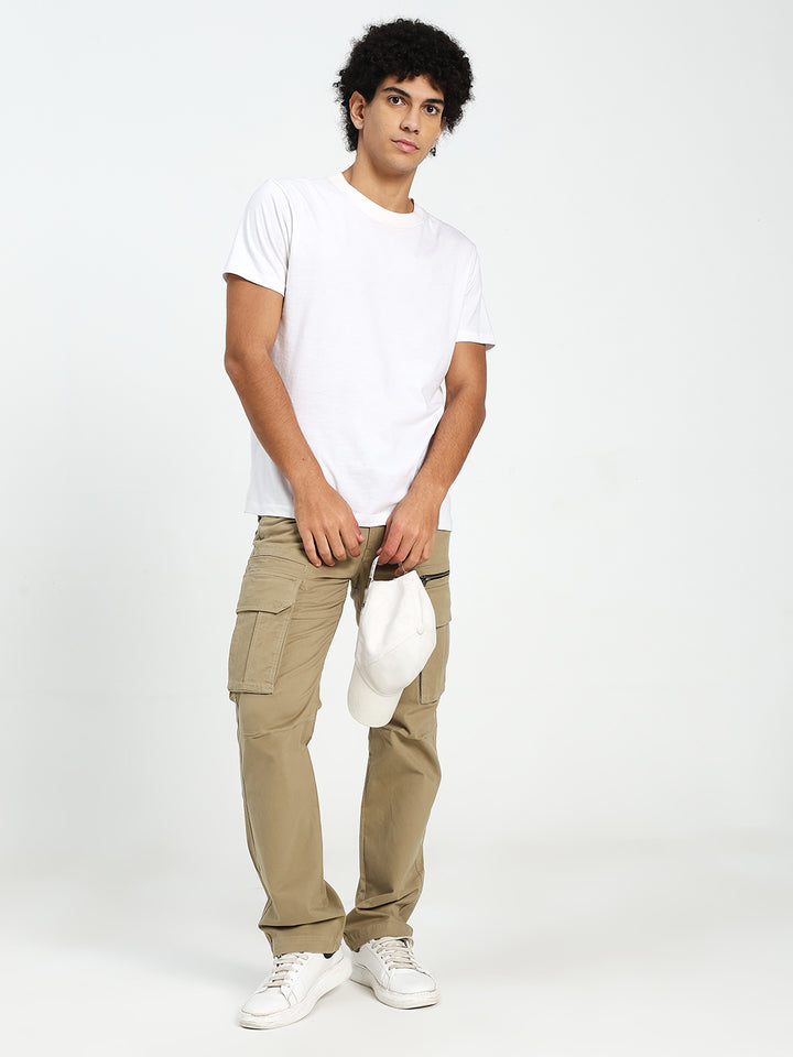 Man wearing a white t-shirt and beige pants holding a white cap on a white background