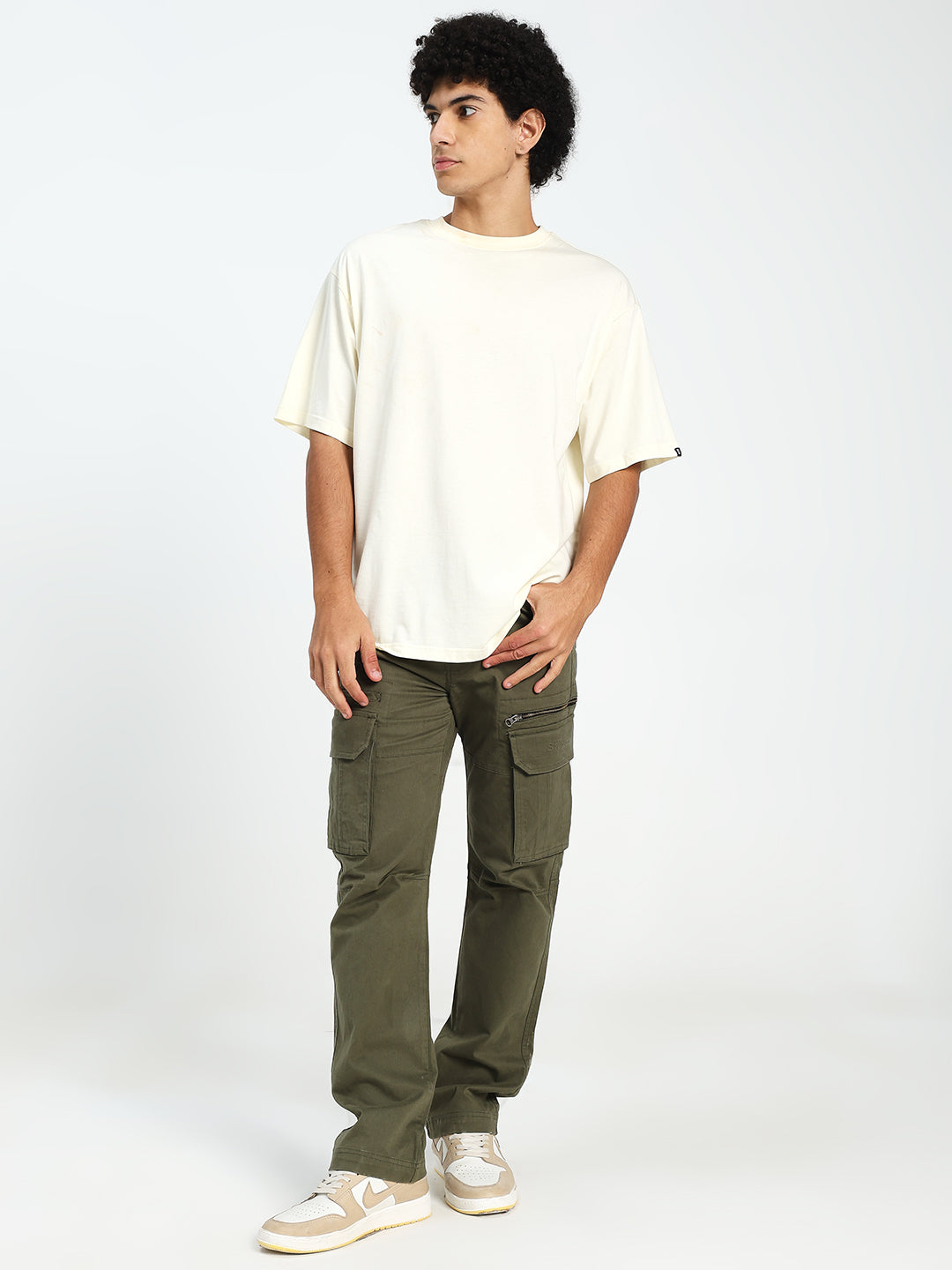 man wearing a white t-shirt and olive green cargo pants on a white background