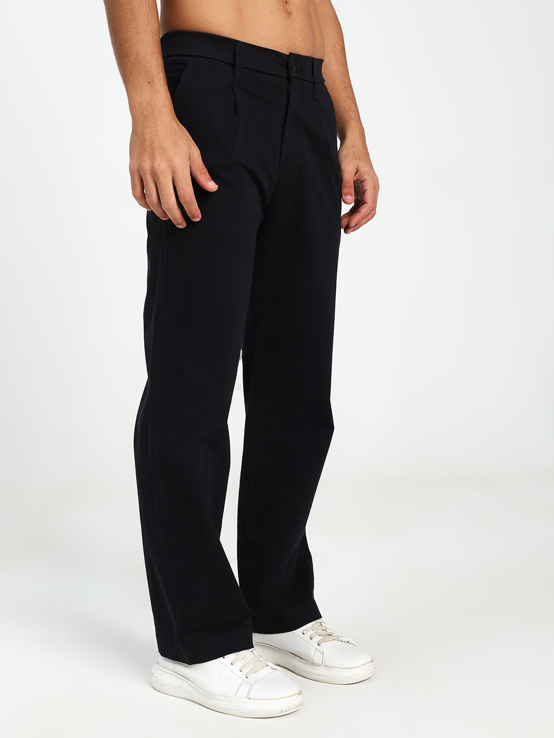 Man wearing black Korean pants and white sneakers on a plain background