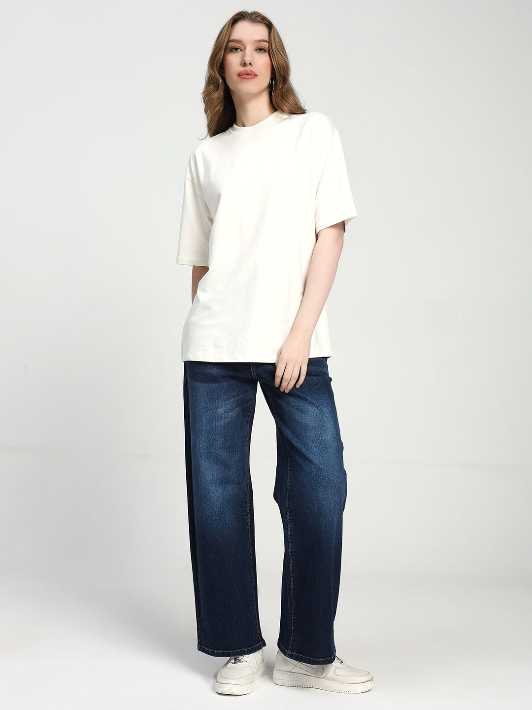 women wearing a white t-shirt and blue jeans on a plain background