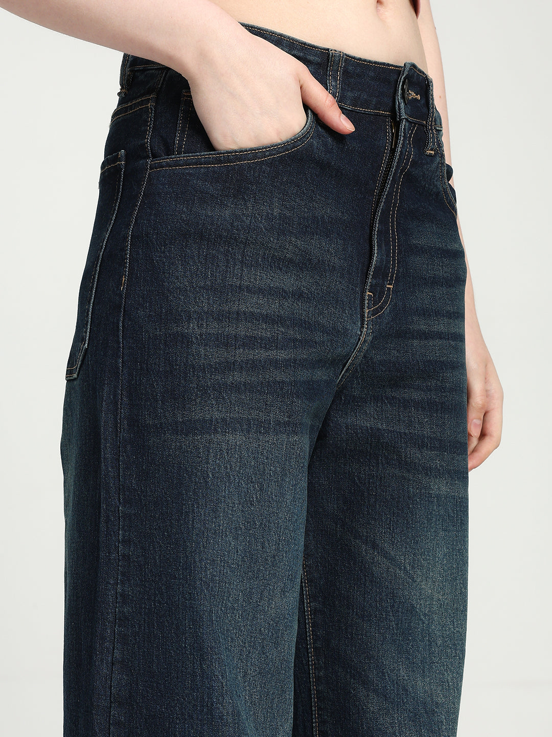 dark blue jeans worn by a women on a plain background