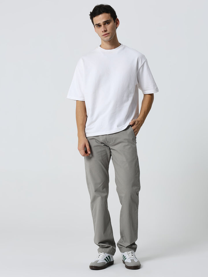 Man wearing a white t-shirt and gray pants on a white background