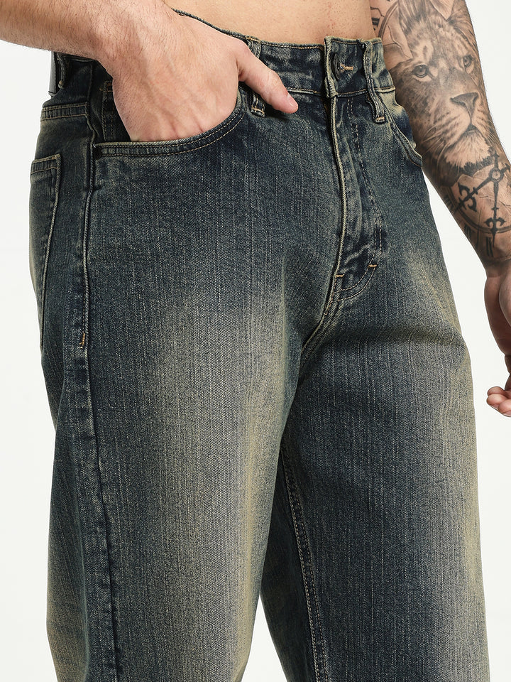man wearing blue jeans with a tattooed arm on a white background