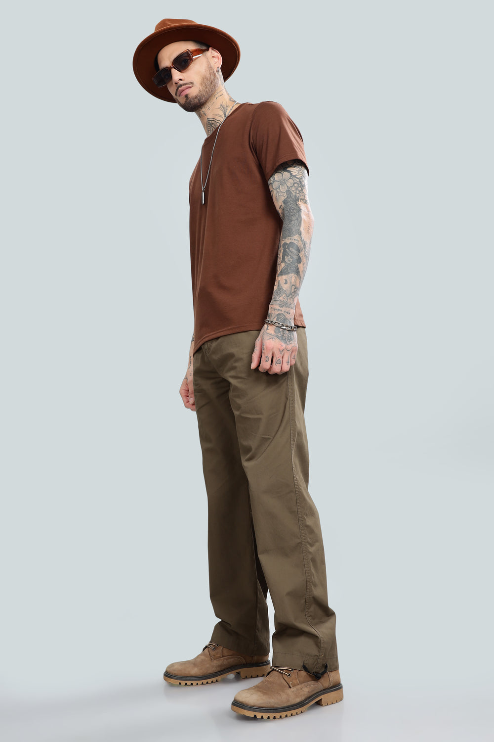 A man model wearing light brown straight pants and a brown shirt with sunglasses.
