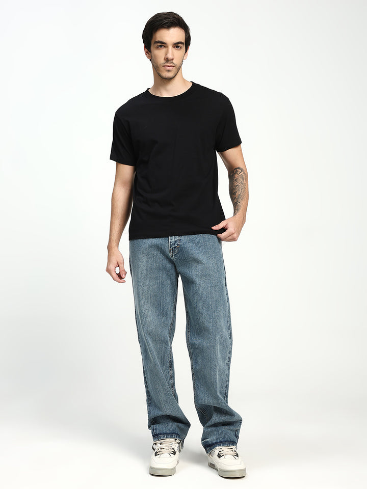 Man wearing a black t-shirt and blue jeans on a white background