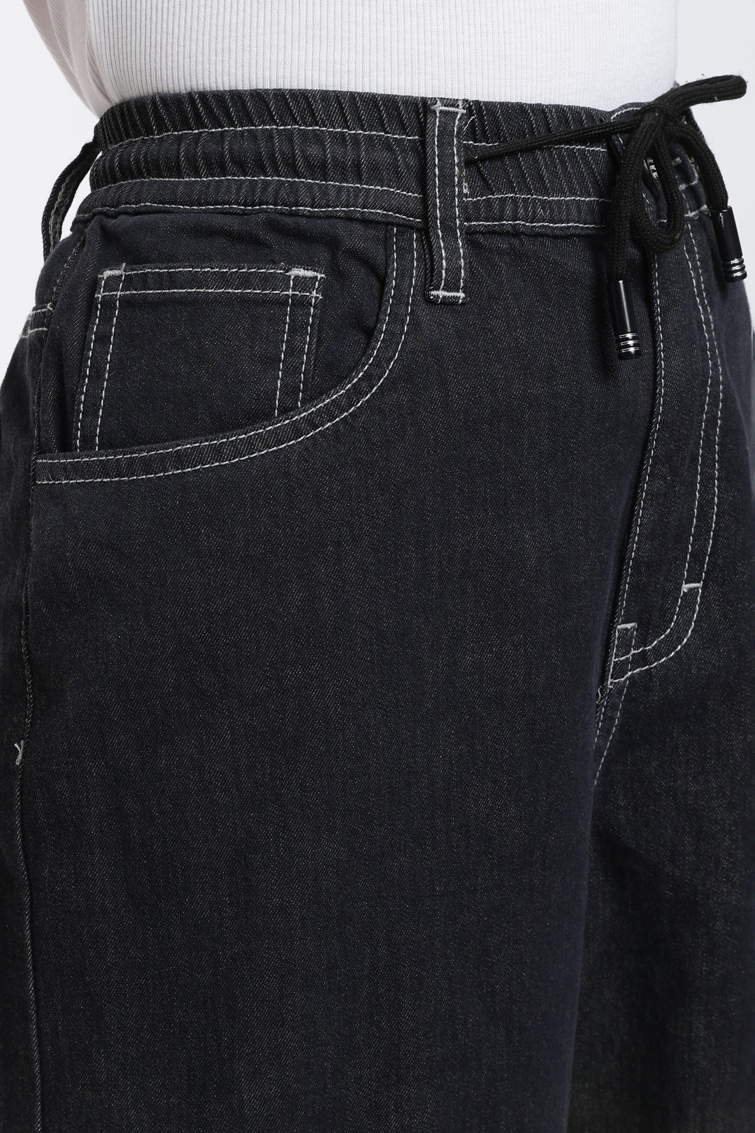 Close-up of dark vintage wash denim jogger with drawstring waistband on a white background