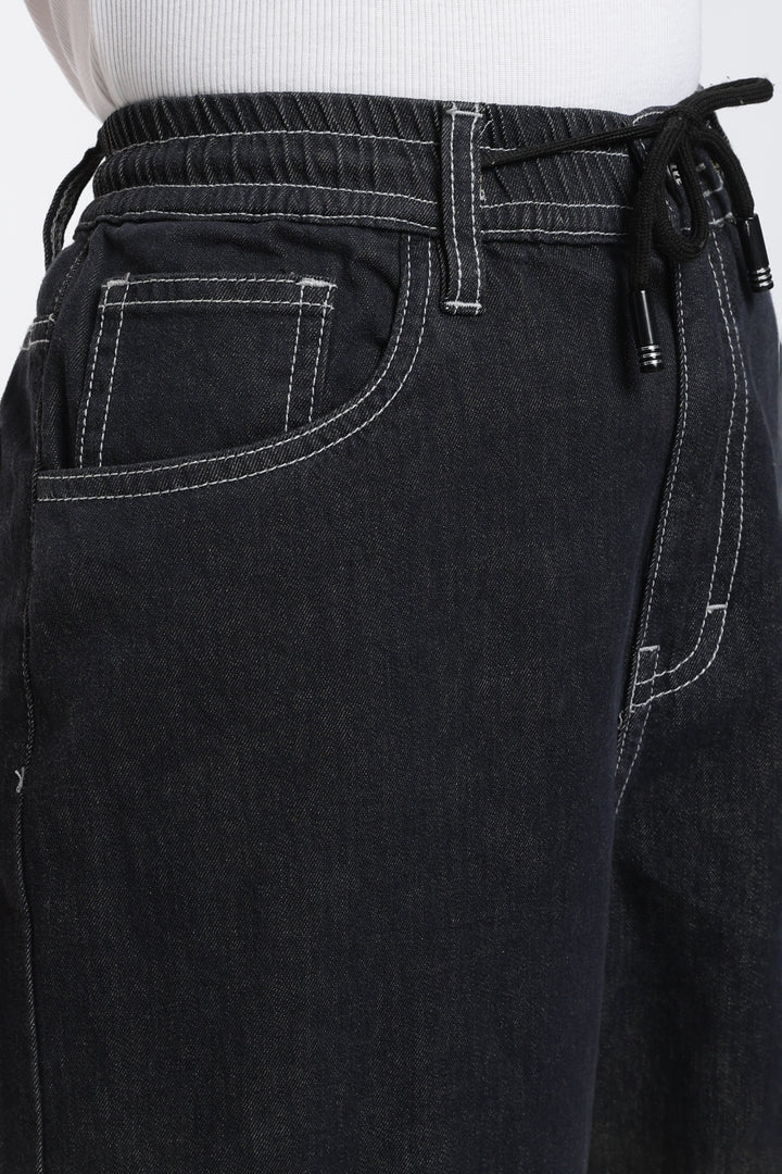 Close-up of dark vintage wash denim jogger with drawstring waistband on a white background