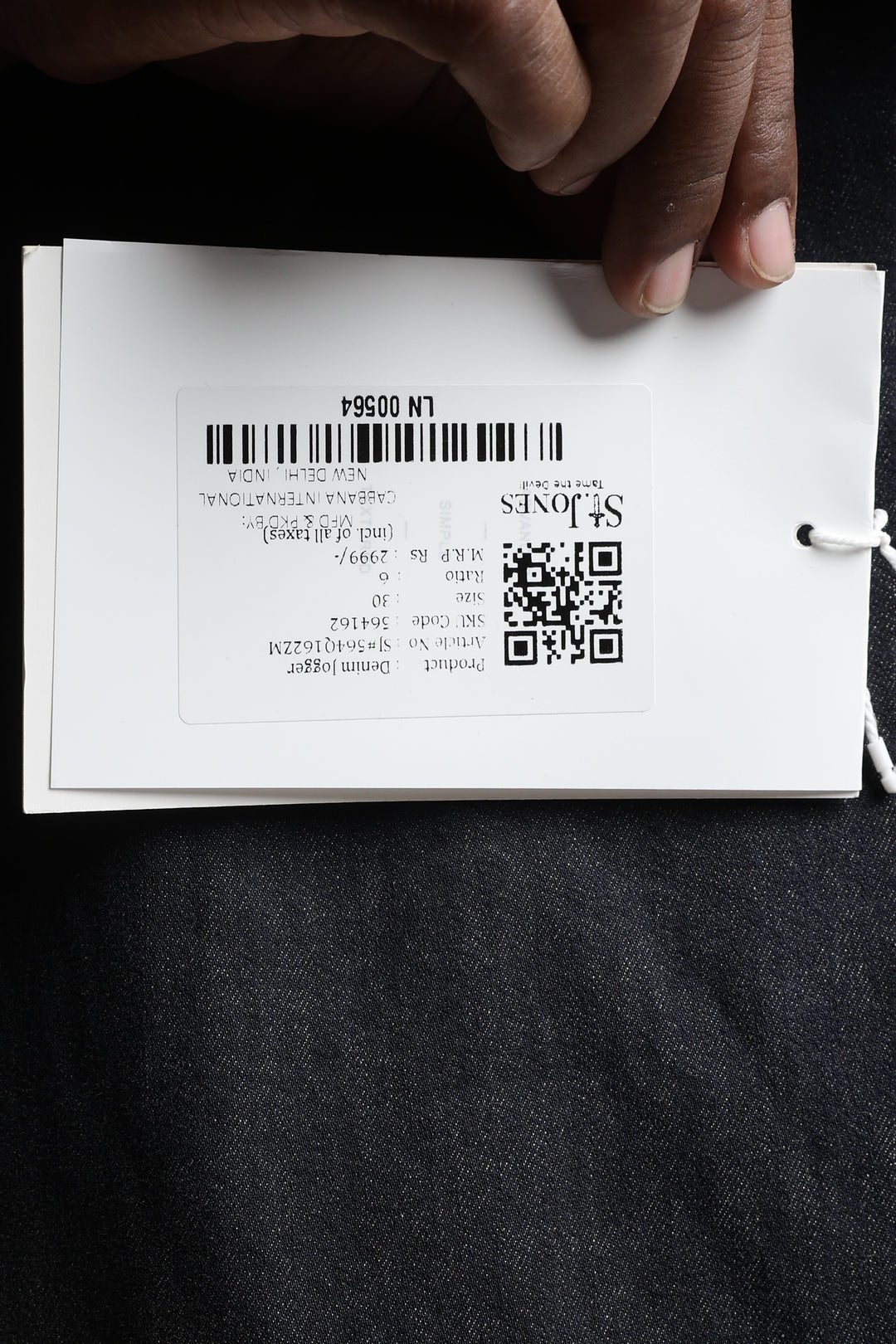Hand holding a white card with text saint jones and QR code on a black background