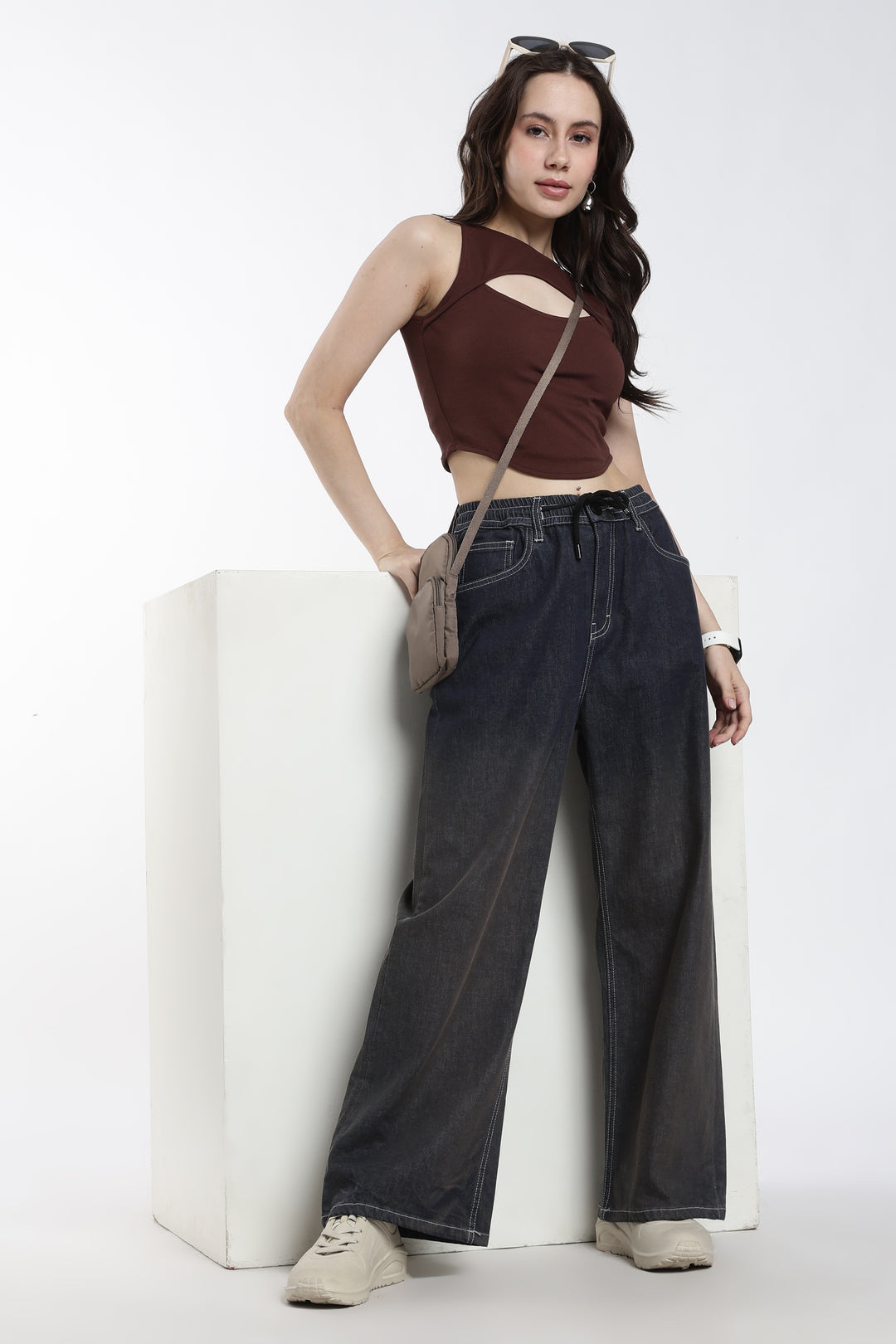 Woman wearing a brown top and vintage wash jogger, standing against a white background