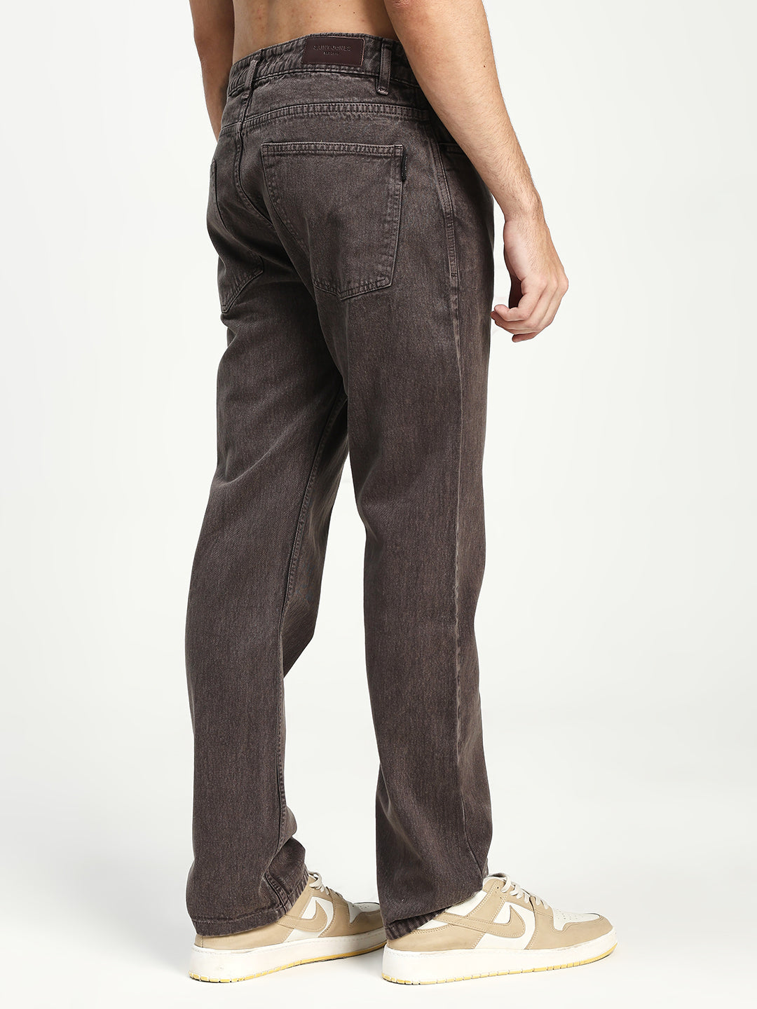 man wearing dark brown ecru jeans on a white background