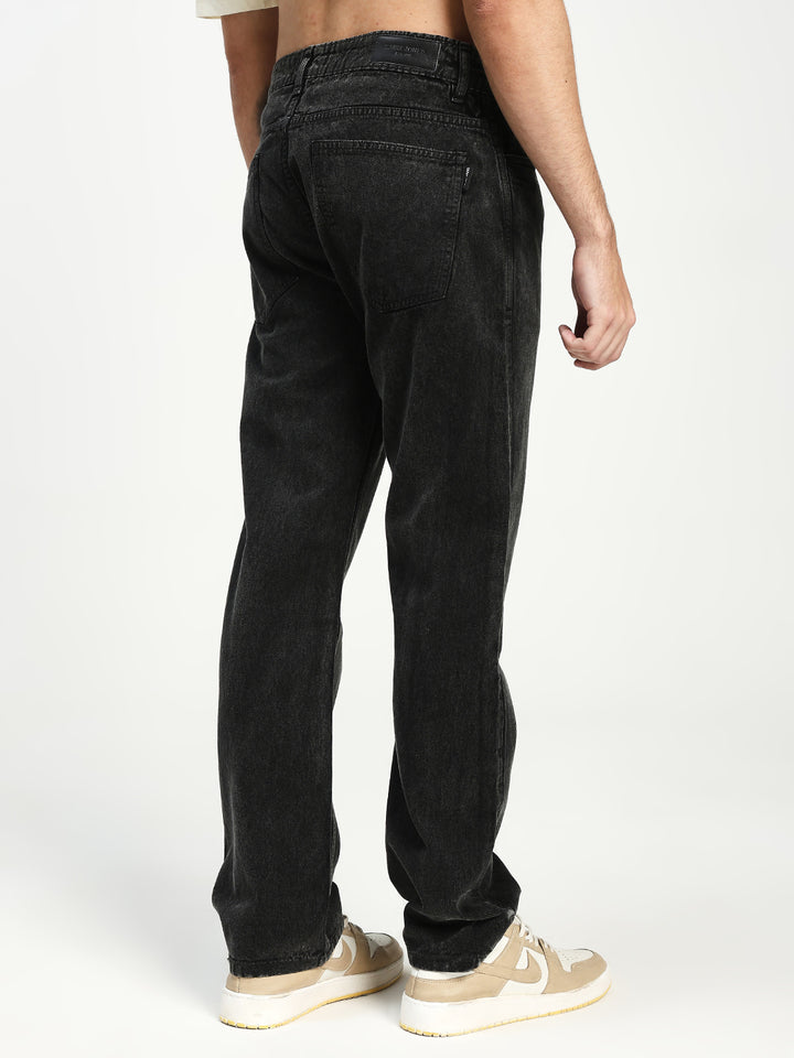 man wearing charcoal acru jeans on a white background