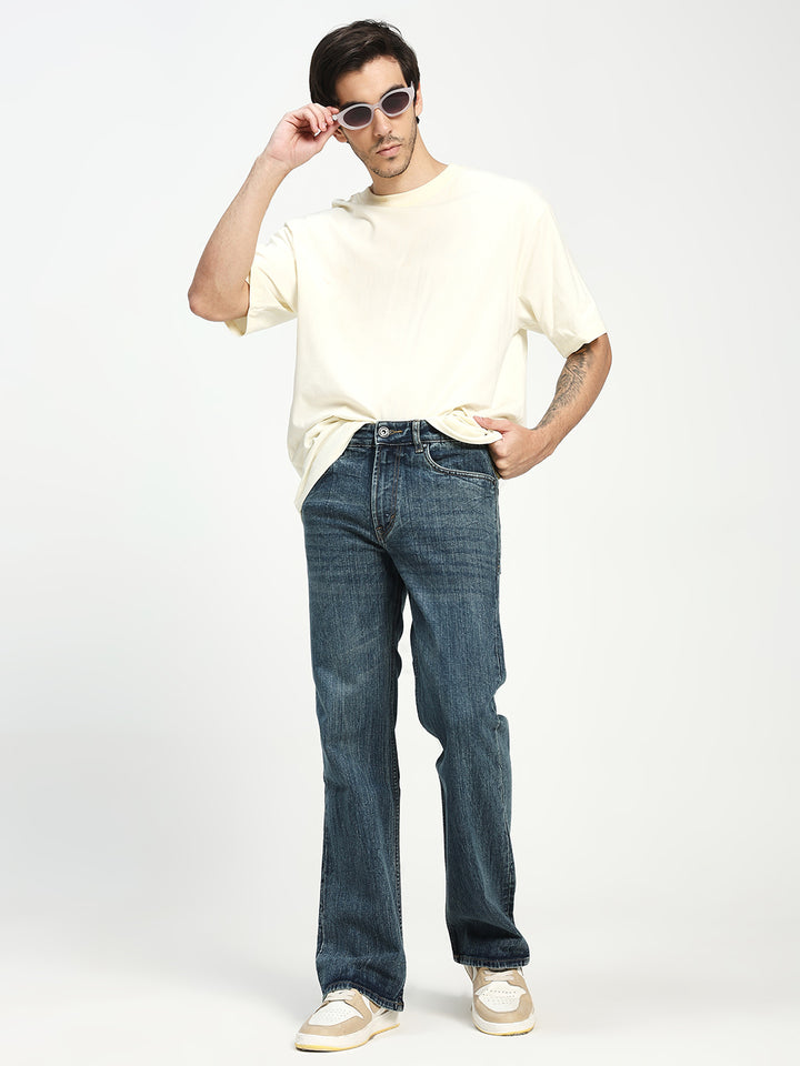 man wearing dark blue bootcut jeans on a white background