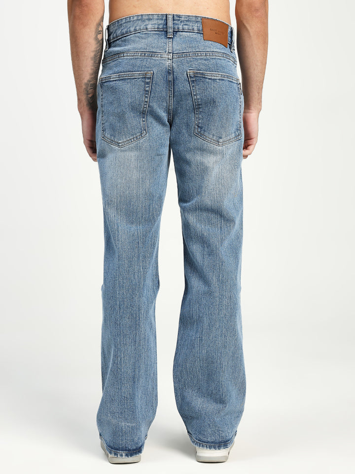 Blue bootcut jeans worn by a man on a white background
