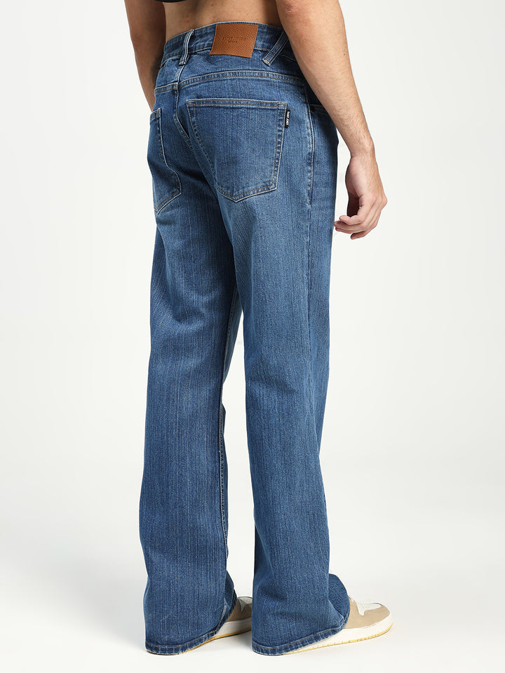 Blue bell bottom jeans worn by a man on a white background