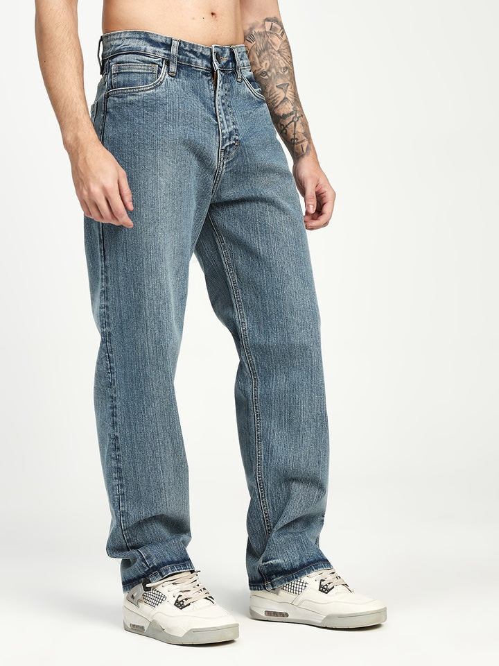 man wearing blue jeans and white sneakers on a plain background