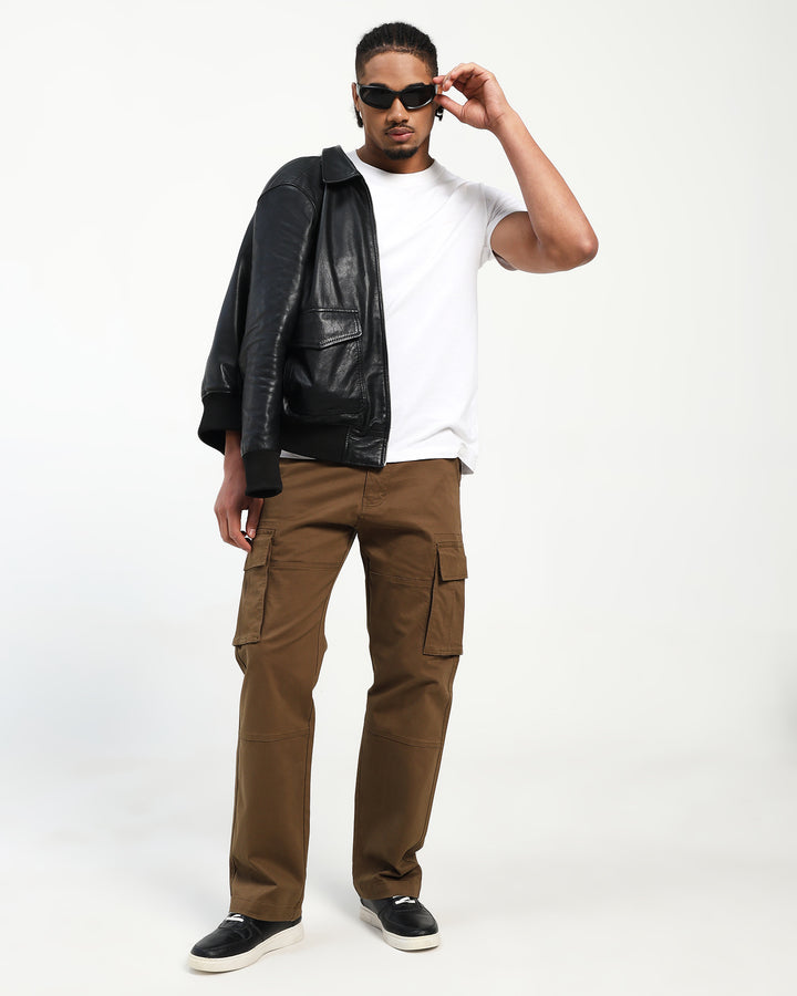 Man wearing a black leather jacket, white t-shirt, and brown cargo pants on a white background