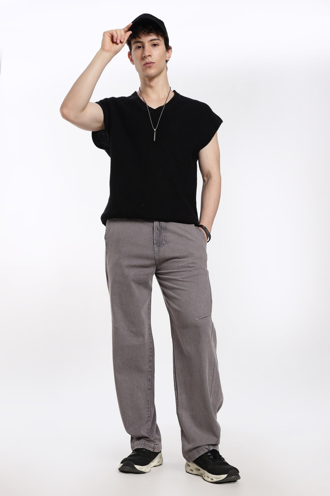 man wearing a black sleeveless t-shirt and gray jogger on a white background