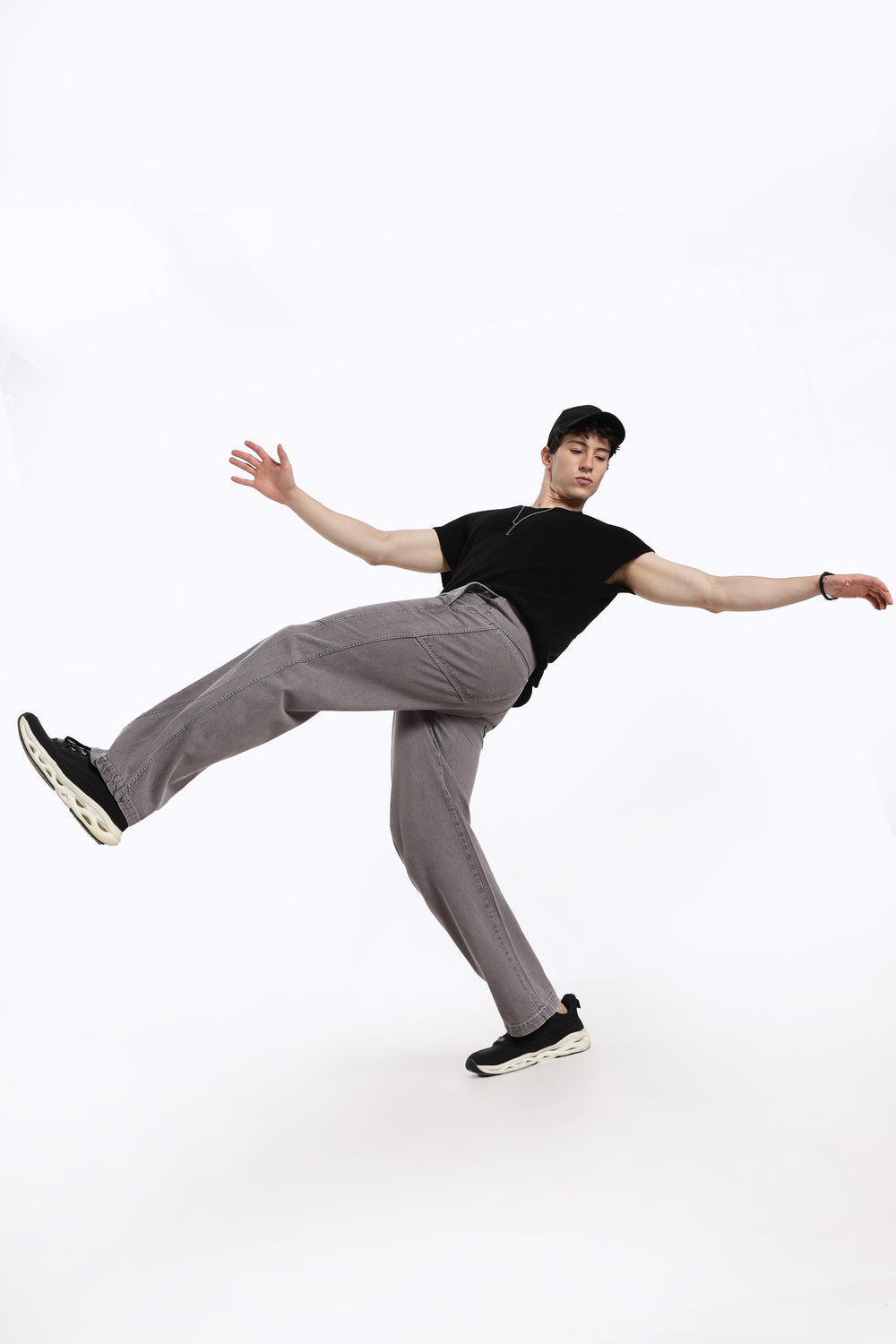 man in black t-shirt and gray jogger posing on a white background
