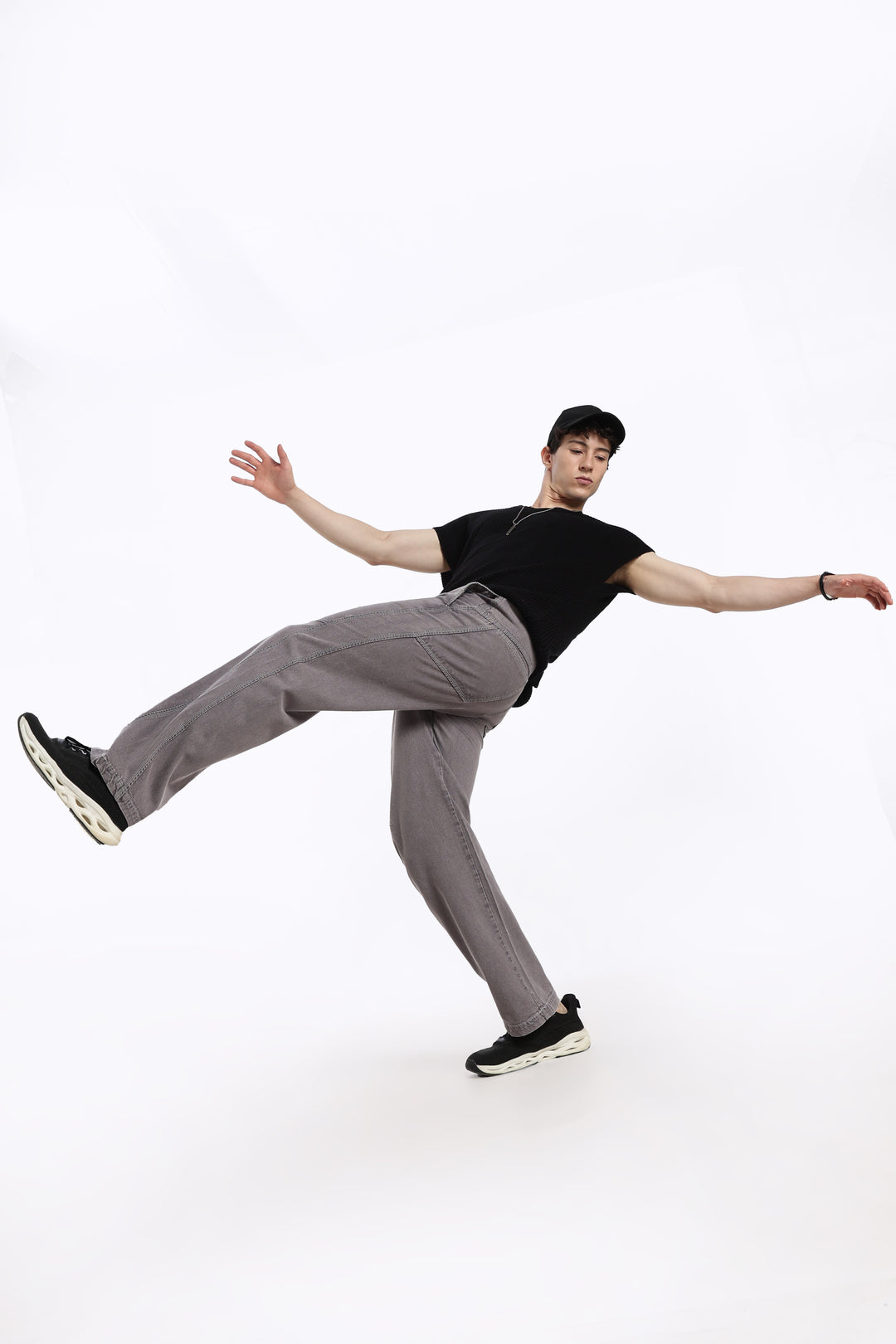 man in black t-shirt and gray jogger posing on a white background